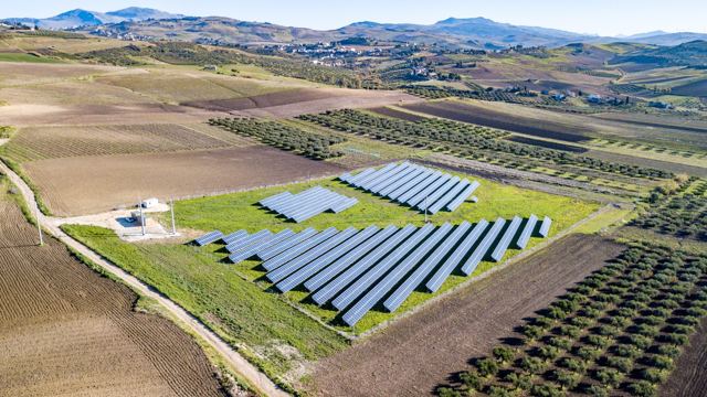 Aerial view of a ground-mounted solar array in open farmland